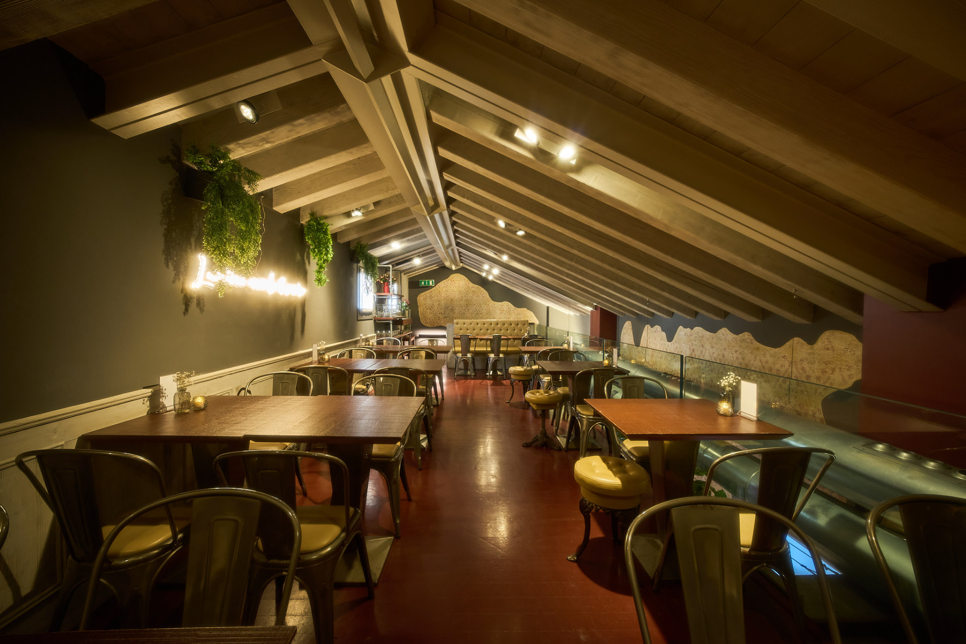 Primo piano del bistrot: travi a vista, tavoli lunghi e atmosfera intima