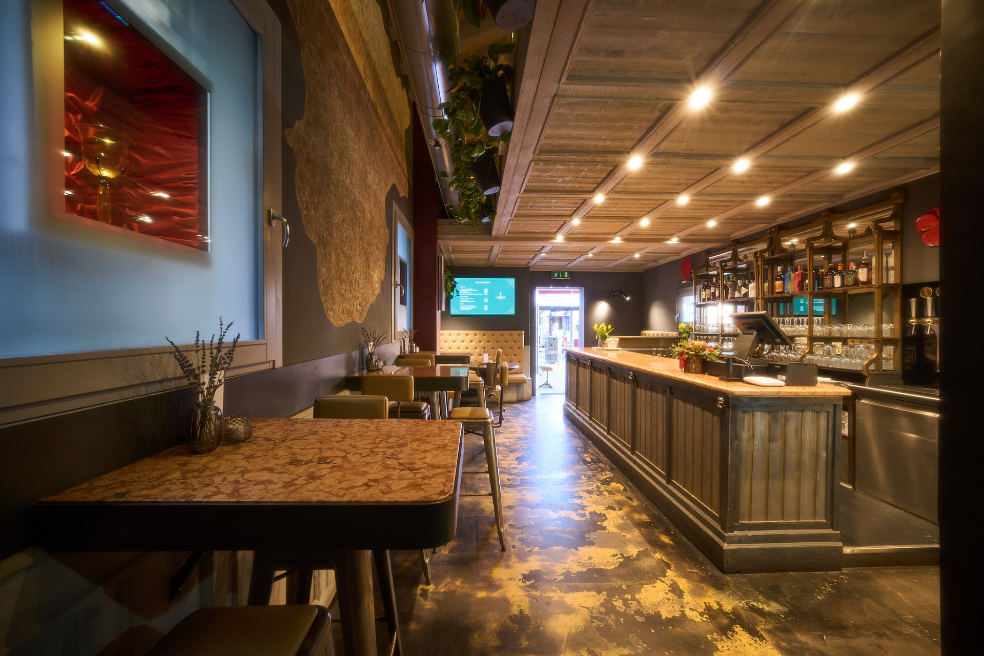 Piano terra del bistrot: bancone in legno, tavolini e luce calda